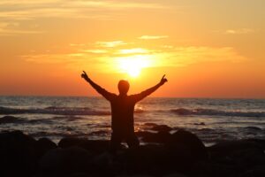 man kneeling on rocks on seashore